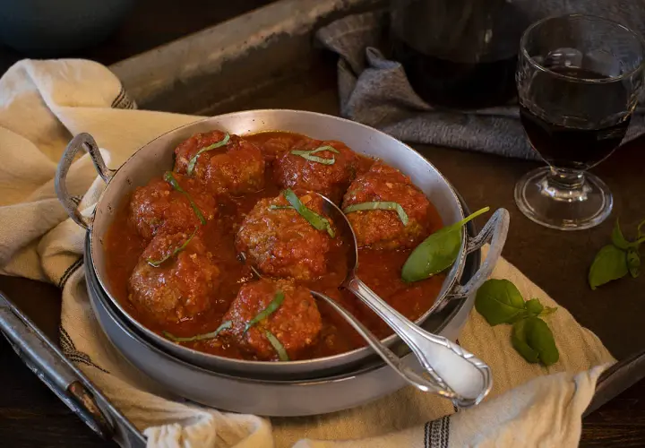 Sabrosas polpette al sugo, jugosas albóndigas en salsa de tomate, adornadas con albahaca fresca.