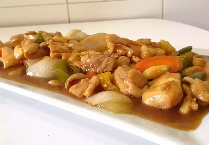 Delicioso pollo con almendras, pimientos y cebolla en una salsa dorada.