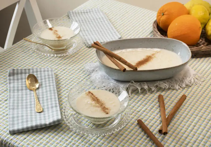 Delicioso arroz con leche sin azúcar, servido en cuencos de cristal y un plato grande, decorado con canela y acompañado de naranjas y limones.