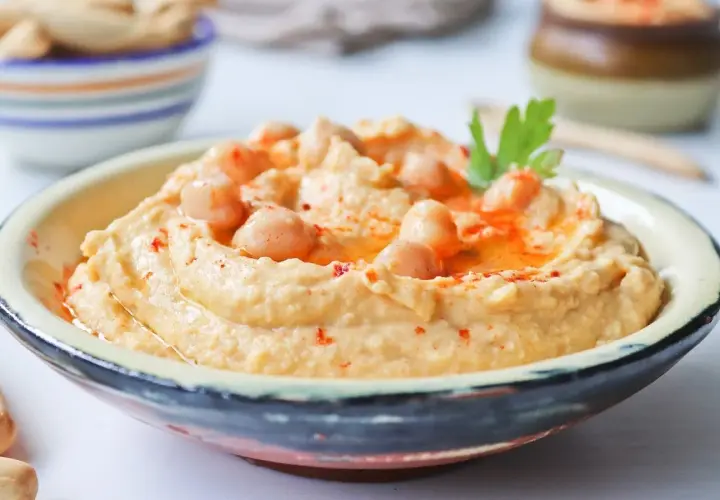 Cremoso hummus de garbanzos, decorado con garbanzos enteros, pimentón y perejil. Perfecto para dipear.