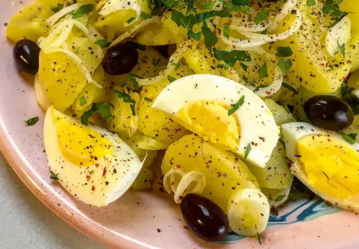 Ensalada de patatas cocidas con huevo duro, aceitunas negras y perejil. Una opción deliciosa para tus recetas con patatas cocidas.