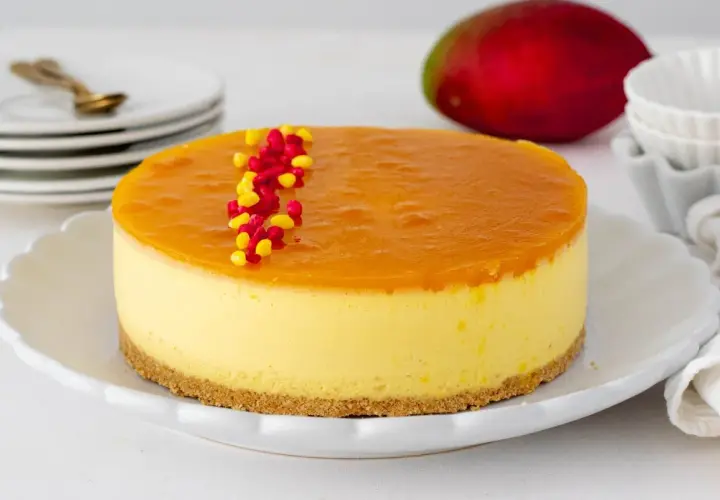 Deliciosa tarta de mango con una capa superior de gelatina brillante y decorada con grageas rojas y amarillas.