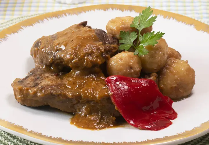 Tierna ternera guisada con patatas, acompañada de pimiento rojo y perejil. Un plato casero y delicioso.