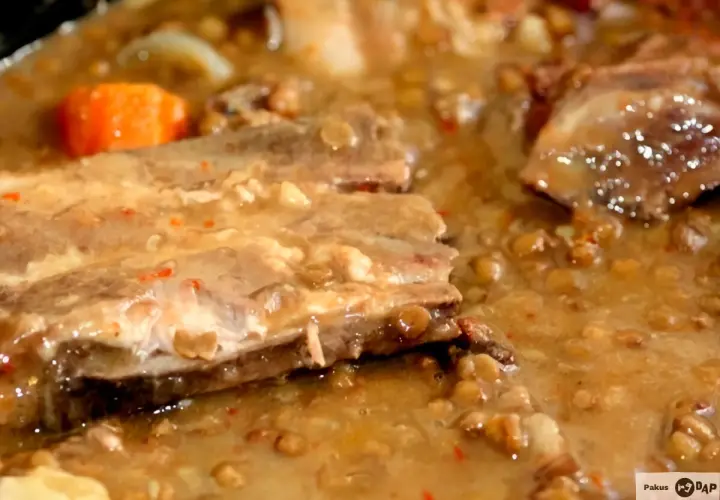 Un plato humeante de lentejas con costillas, con trozos de zanahoria y un caldo espeso y sabroso.