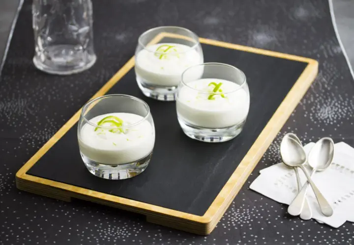 Tres vasitos de cremoso mousse de limón, decorados con ralladura verde, listos para disfrutar.