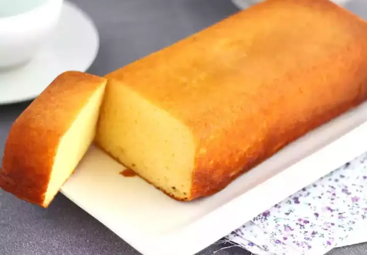 Un delicioso bizcocho de leche condensada, dorado y esponjoso, servido en una bandeja blanca.
