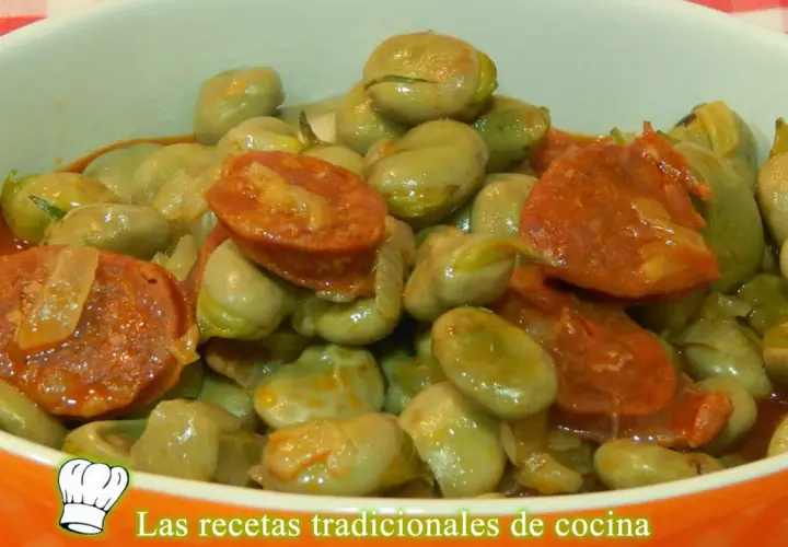 Un plato humeante de habas tiernas con rodajas de chorizo español, todo bañado en una salsa sabrosa.