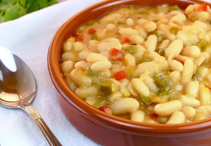 Judías blancas de bote salteadas con pimientos y cebolla, servidas en cuenco de barro.