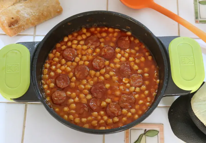 Un plato humeante de garbanzos con chorizo, listo para disfrutar con pan crujiente.