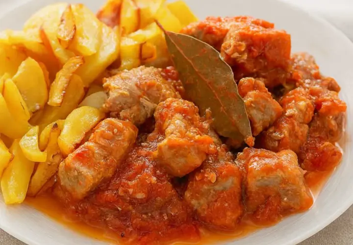 Magro con tomate, la receta de la abuela, servido con patatas fritas doradas. Un plato casero lleno de sabor.