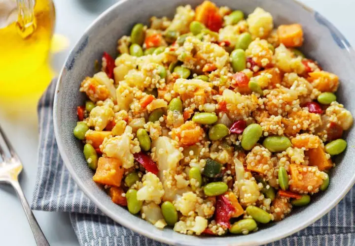 Un tazón de quinoa con verduras coloridas: edamame, coliflor, zanahoria y pimiento rojo. Un plato saludable y delicioso.