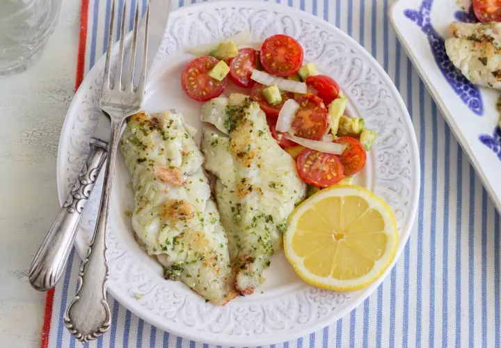 Deliciosa gallineta a la plancha con ensalada de tomate y aguacate, acompañada de un gajo de limón.