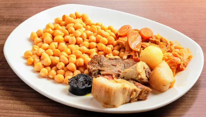 Plato de cocido en olla express con garbanzos, carne, morcilla, patatas y verduras.