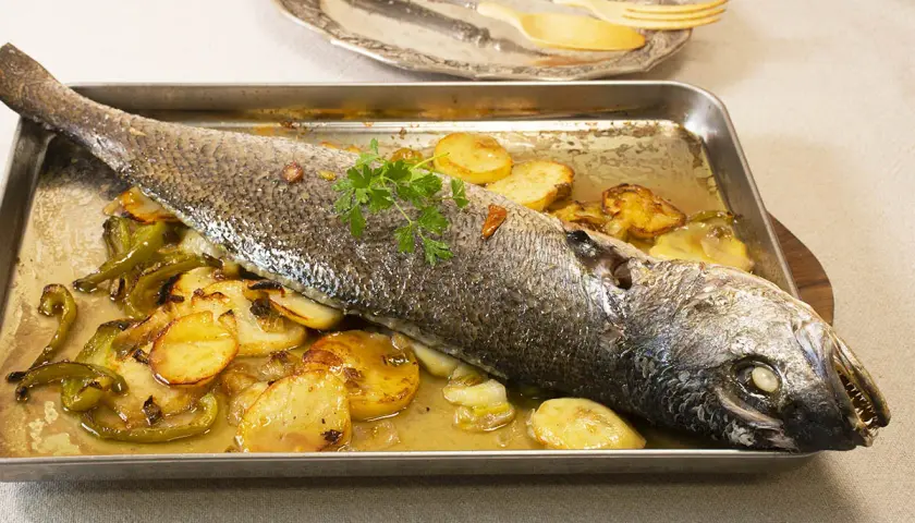 Corvina al horno con patatas y pimientos, lista para servir.