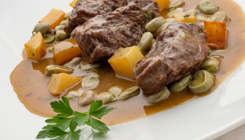 Carrilleras al horno, un plato de Karlos Arguiñano, con habas y trozos de calabaza en una salsa sabrosa.