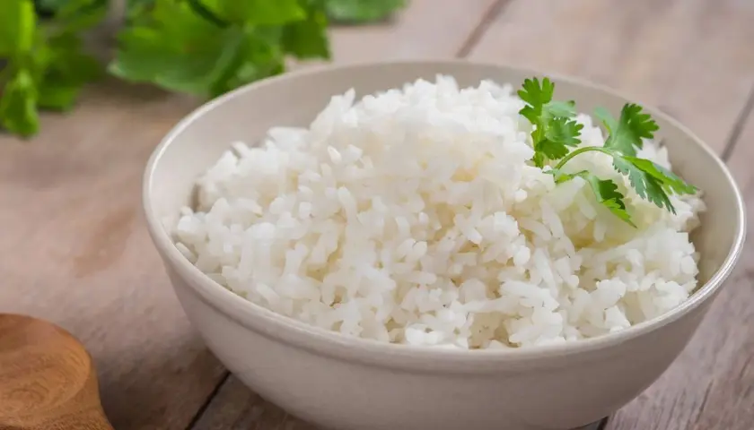 Un tazón de arroz blanco recién cocido, decorado con cilantro fresco. ¿Te preguntas cuánto dura el arroz en la nevera?