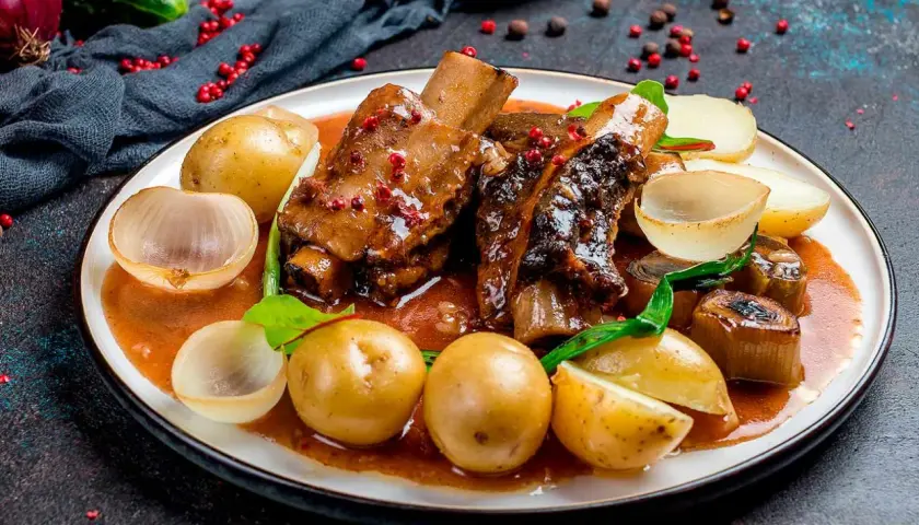 Costillas al horno con patatas, cebolla y un toque de vino blanco. Un plato jugoso y lleno de sabor.