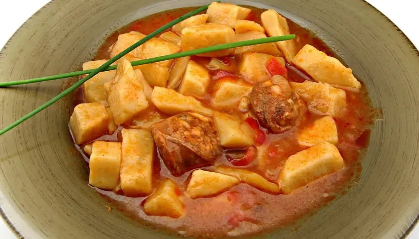 Patatas a la riojana arguiñano, un plato casero con trozos de patata, chorizo y pimiento en una salsa roja, decorado con cebollino.