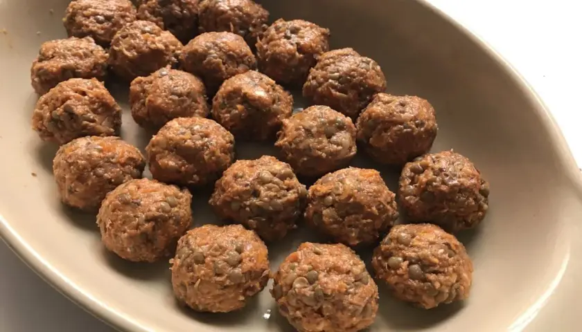 Albondigas de lentejas listas para hornear en una bandeja.