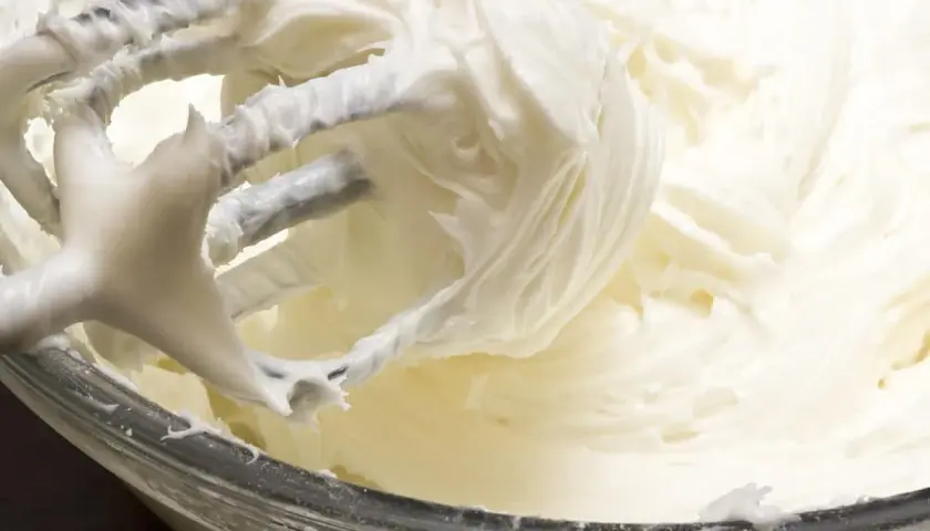 Batidora mezclando un cremoso frosting de queso, listo para decorar.