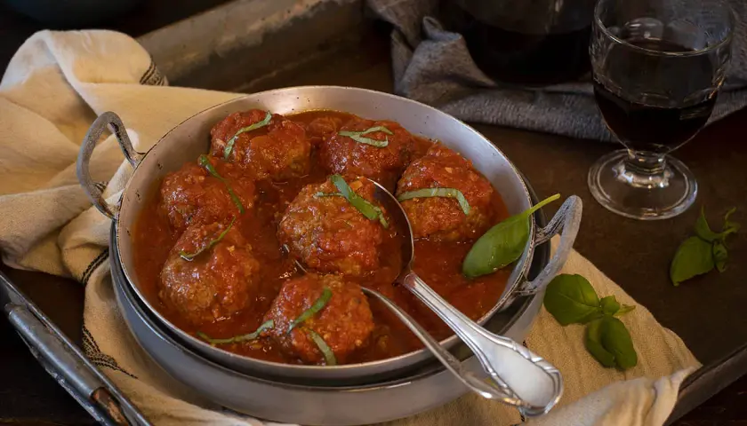 Sabrosas polpette al sugo, jugosas albóndigas en salsa de tomate, adornadas con albahaca fresca.