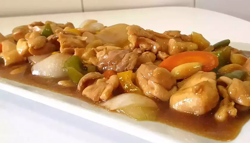 Delicioso pollo con almendras, pimientos y cebolla en una salsa dorada.