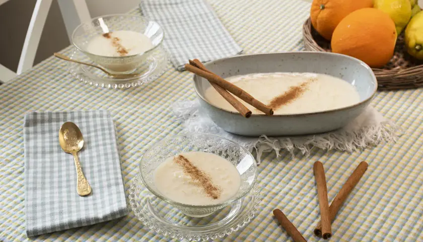 Delicioso arroz con leche sin azúcar, servido en cuencos de cristal y un plato grande, decorado con canela y acompañado de naranjas y limones.