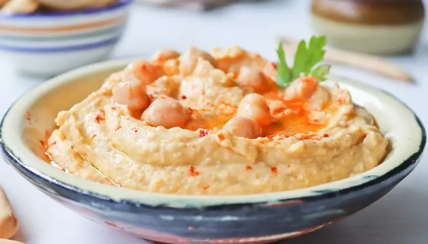 Cremoso hummus de garbanzos, decorado con garbanzos enteros, pimentón y perejil. Perfecto para dipear.