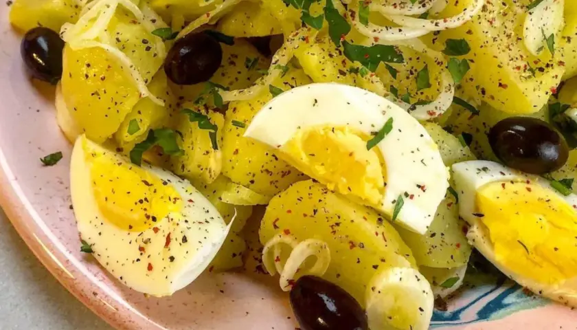 Ensalada de patatas cocidas con huevo duro, aceitunas negras y perejil. Una opción deliciosa para tus recetas con patatas cocidas.
