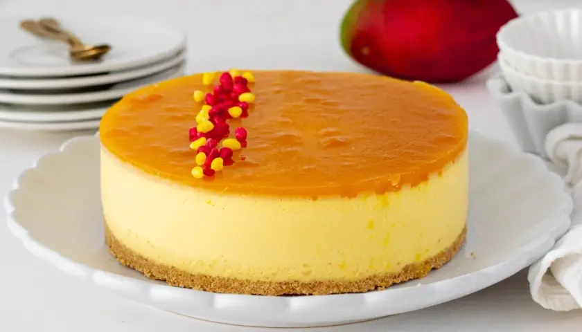 Deliciosa tarta de mango con una capa superior de gelatina brillante y decorada con grageas rojas y amarillas.