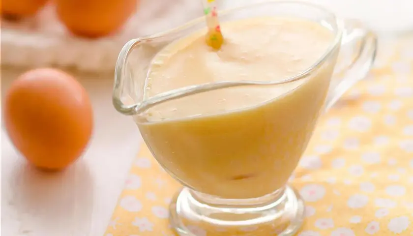 Crema pastelera perfecta hecha en Thermomix, lista para usar. Huevos frescos en el fondo.