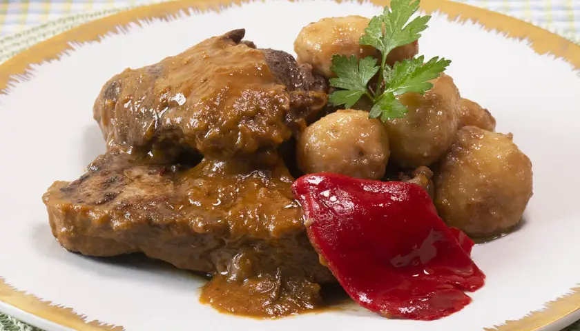 Tierna ternera guisada con patatas, acompañada de pimiento rojo y perejil. Un plato casero y delicioso.