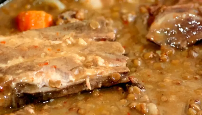 Un plato humeante de lentejas con costillas, con trozos de zanahoria y un caldo espeso y sabroso.