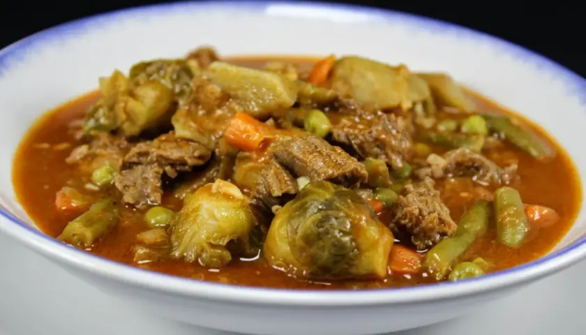 Un reconfortante plato de menestra de verduras con carne de la abuela, lleno de tiernos trozos de carne, coles de Bruselas, zanahorias y judías verdes en una rica salsa.