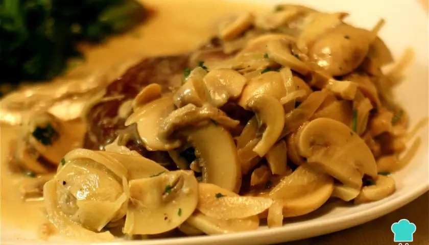 Un delicioso lomo con champiñones en salsa cremosa, acompañado de espinacas. ¡Un plato principal irresistible!