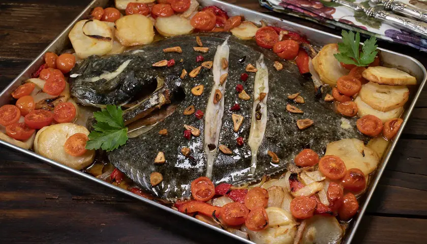 Rodaballo al horno con patatas, tomates cherry y ajo, un plato que evoca la cocina de Arzak.