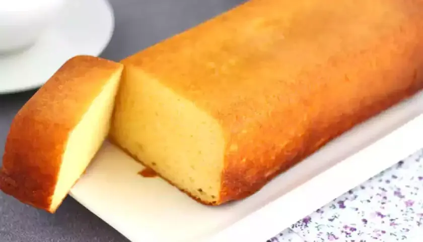 Un delicioso bizcocho de leche condensada, dorado y esponjoso, servido en una bandeja blanca.