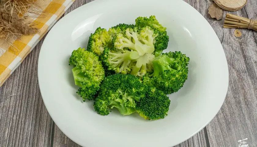 Brocoli al vapor, fresco y verde, servido en un plato blanco. Un toque saludable y delicioso.