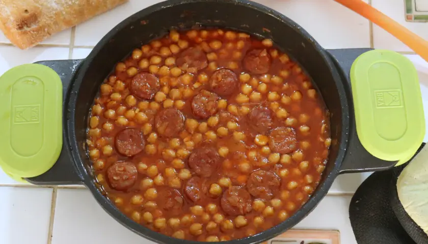 Un plato humeante de garbanzos con chorizo, listo para disfrutar con pan crujiente.