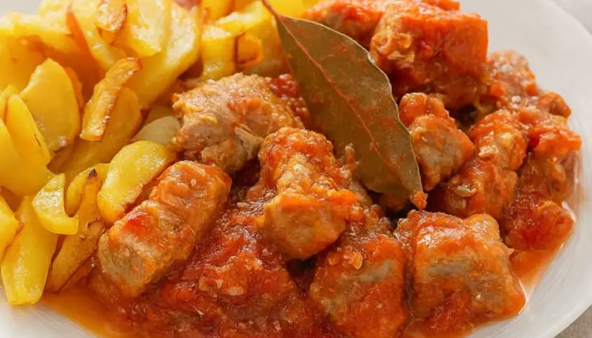 Magro con tomate, la receta de la abuela, servido con patatas fritas doradas. Un plato casero lleno de sabor.