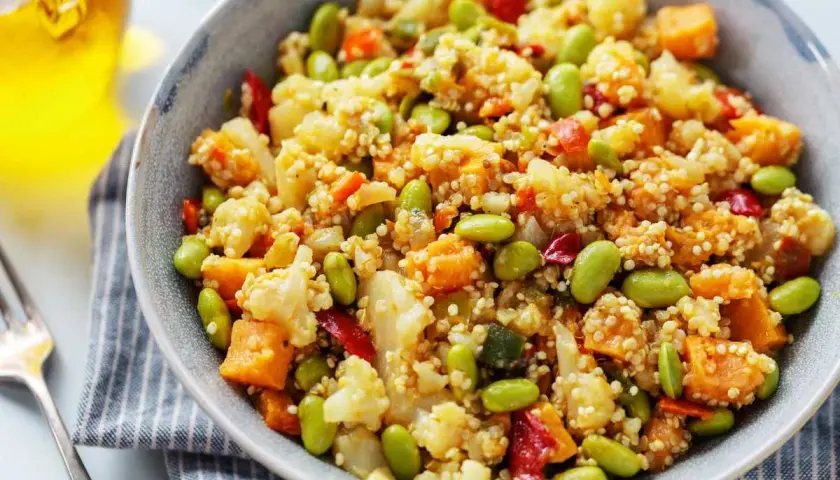 Un tazón de quinoa con verduras coloridas: edamame, coliflor, zanahoria y pimiento rojo. Un plato saludable y delicioso.