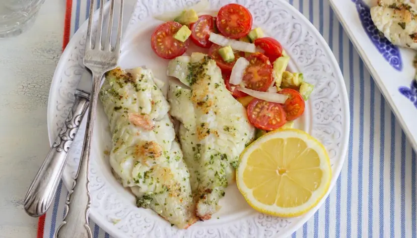 Deliciosa gallineta a la plancha con ensalada de tomate y aguacate, acompañada de un gajo de limón.