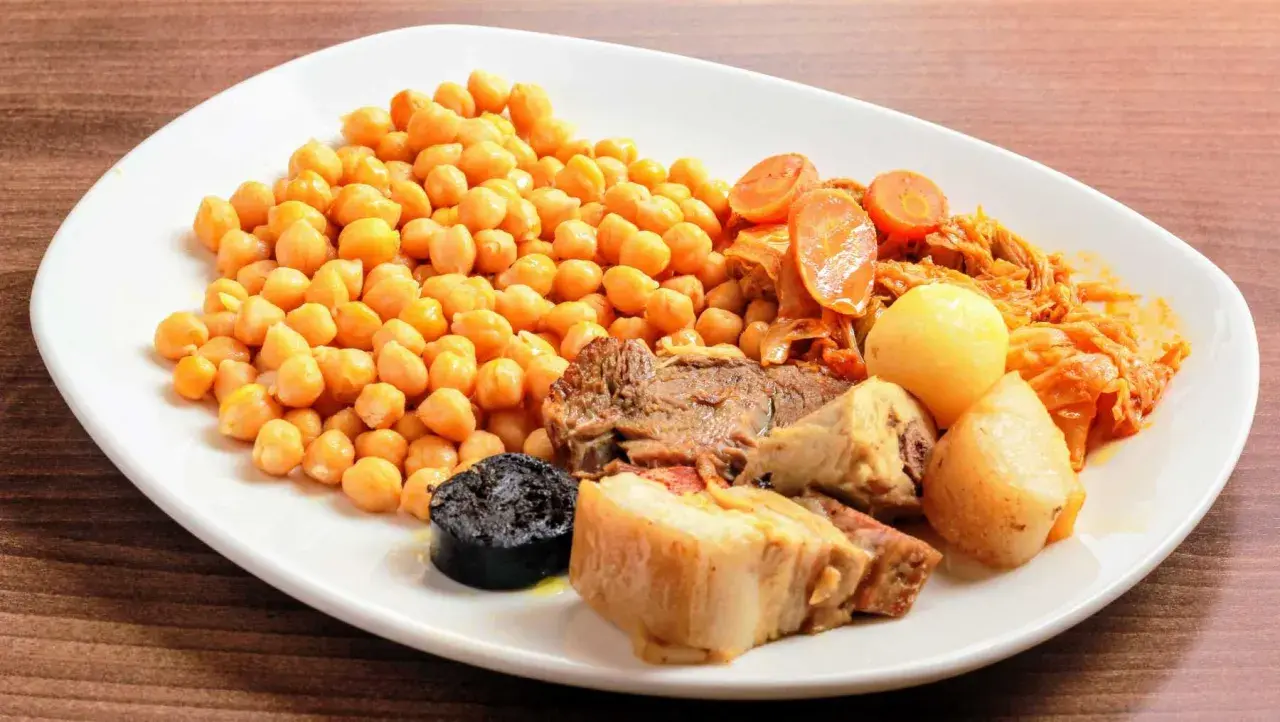 Plato de cocido en olla express con garbanzos, carne, morcilla, patatas y verduras.