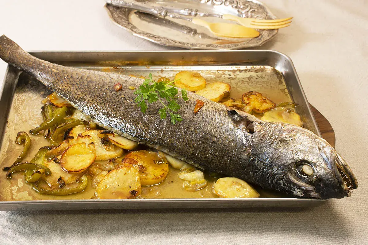 Corvina al horno con patatas y pimientos, lista para servir.