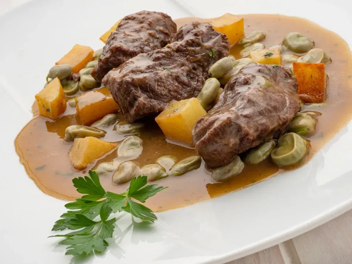 Carrilleras al horno, un plato de Karlos Arguiñano, con habas y trozos de calabaza en una salsa sabrosa.