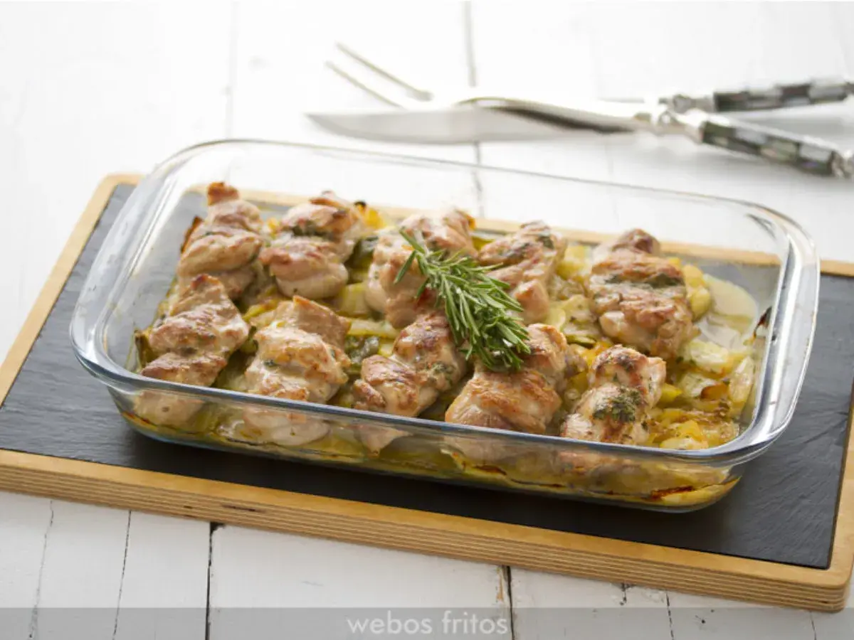 Contramuslos de pollo al horno crujientes, dorados y jugosos, servidos en una fuente de cristal con patatas y romero.