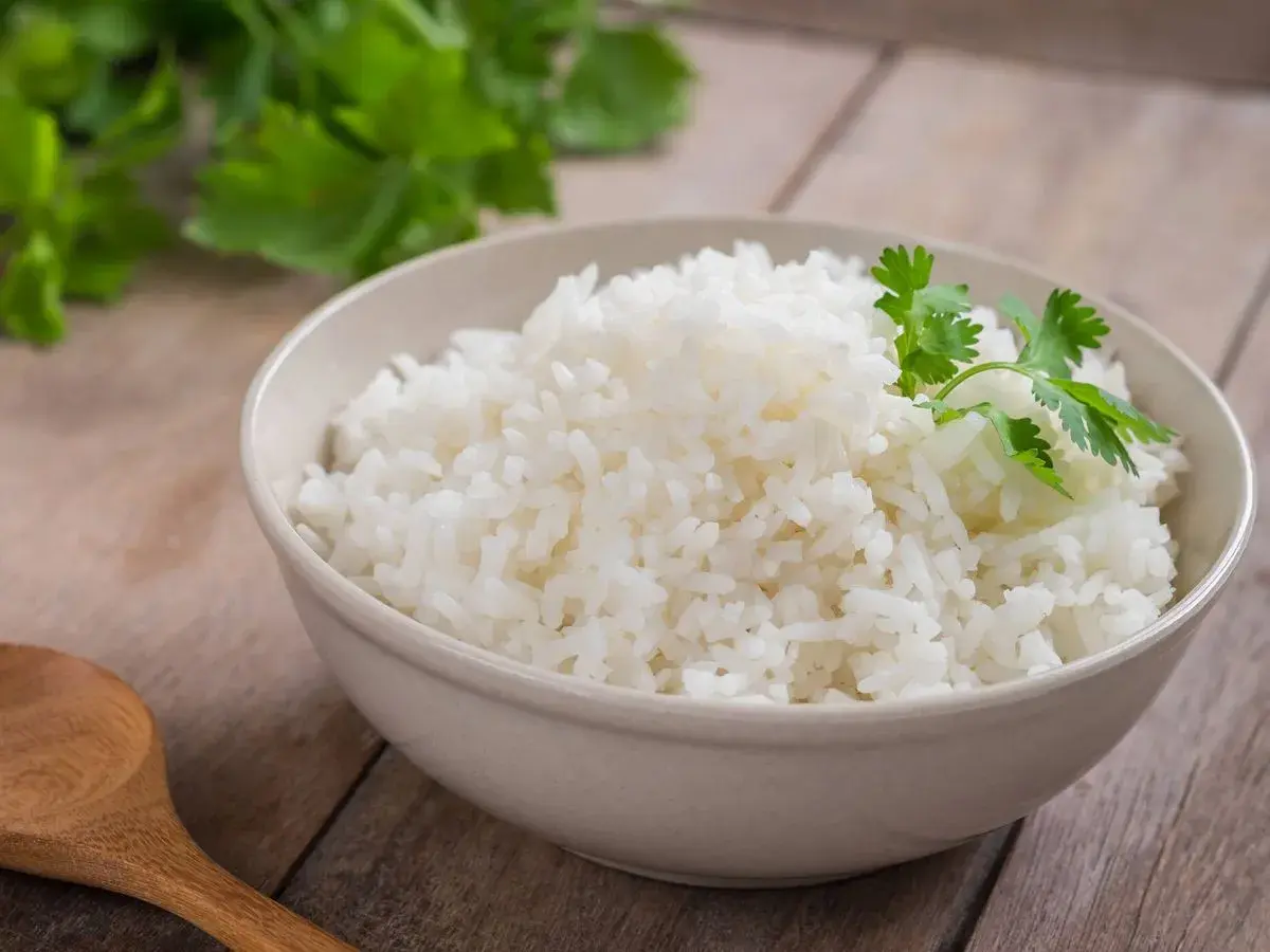 Un tazón de arroz blanco recién cocido, decorado con cilantro fresco. ¿Te preguntas cuánto dura el arroz en la nevera?