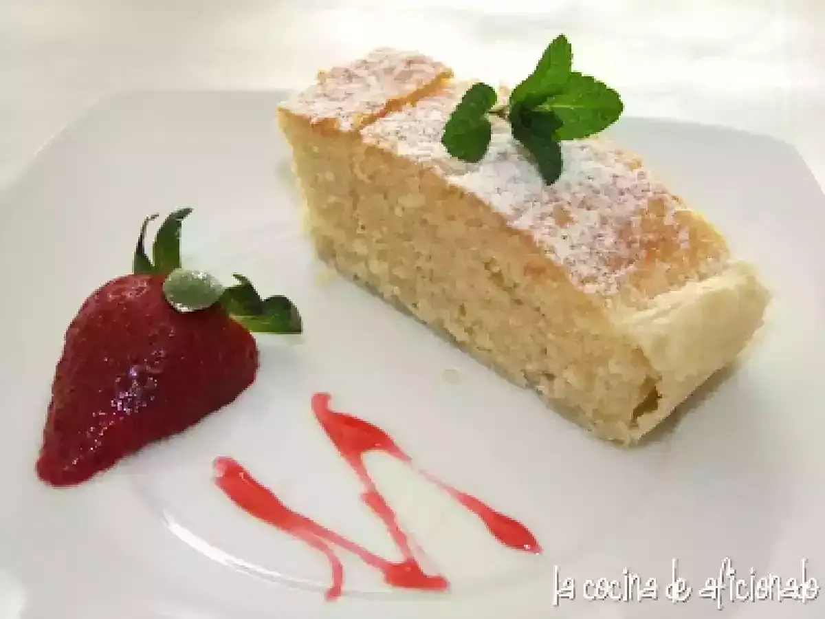 Un delicioso bizcocho de almendras espolvoreado con azúcar glas, decorado con una fresa y menta.