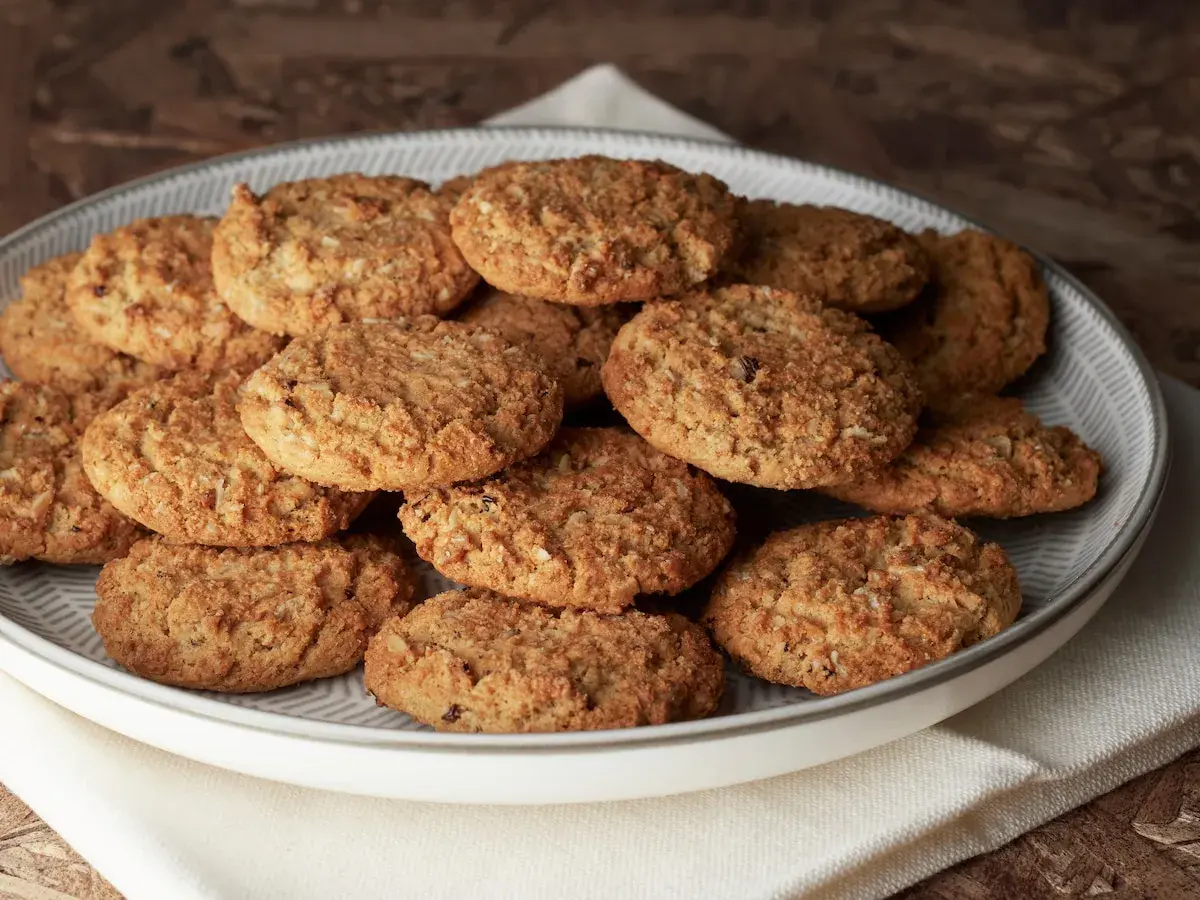 Montón de carajitos del profesor, galletas doradas y crujientes con avena y coco, apiladas en un plato gris.