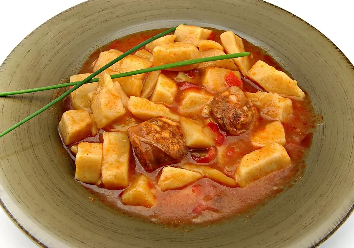 Patatas a la riojana arguiñano, un plato casero con trozos de patata, chorizo y pimiento en una salsa roja, decorado con cebollino.